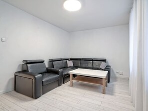 A modern living room with a sectional sofa, a coffee table, and a light-colored wooden floor.