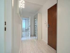 Un couloir avec une porte en bois, une porte en verre et un mur blanc.