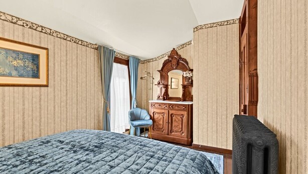 Ein Hotelzimmer mit Bett, Kommode, Stuhl und Spiegel.
