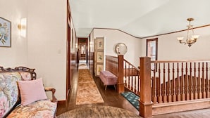 Ein Flur mit einer Holztreppe, einem Sofa mit floralem Bezug und einem gemusterten Teppich.