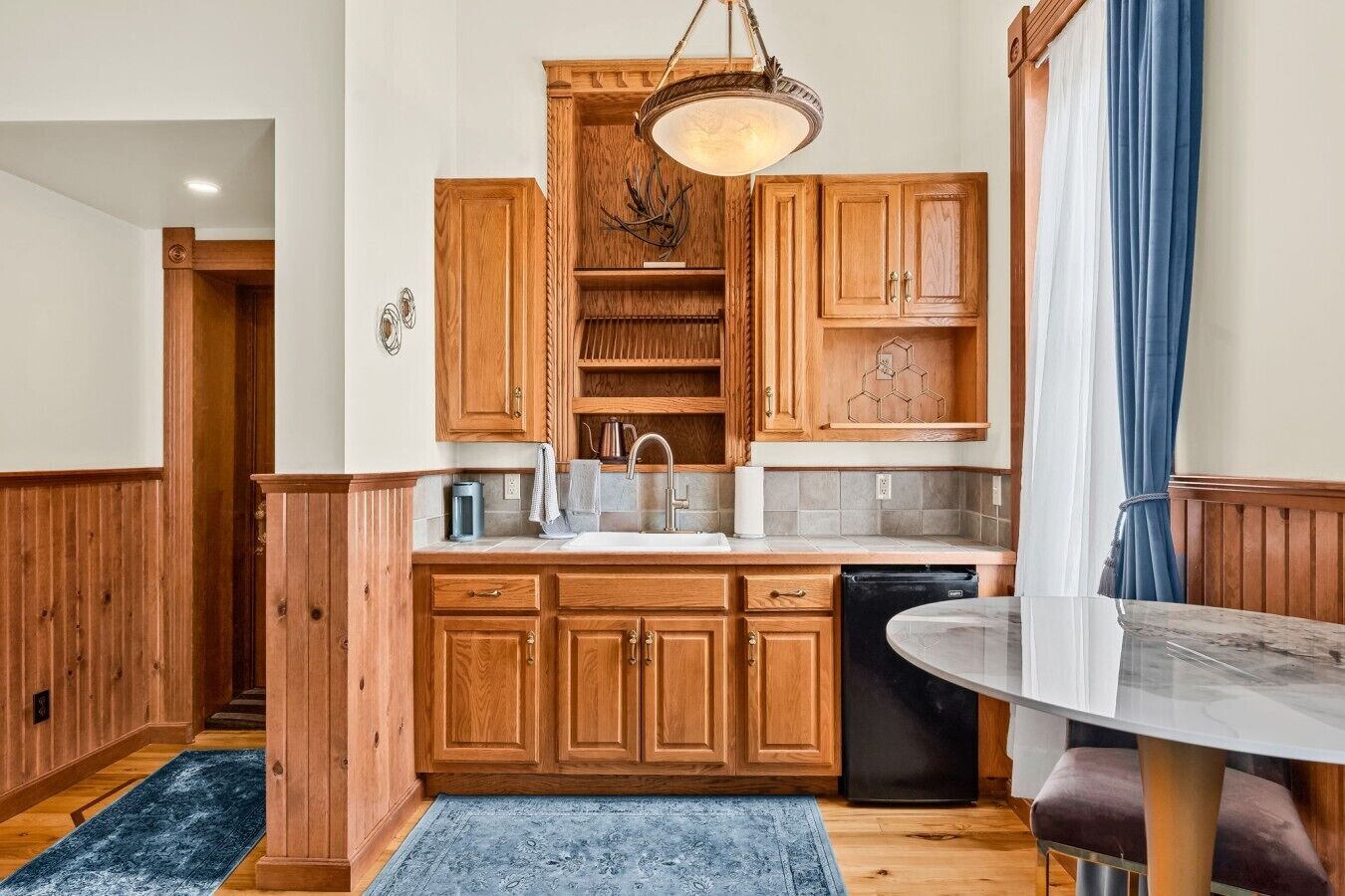 Een keuken met houten kastjes, een spoelbak, een vaatwasser en een eettafel.