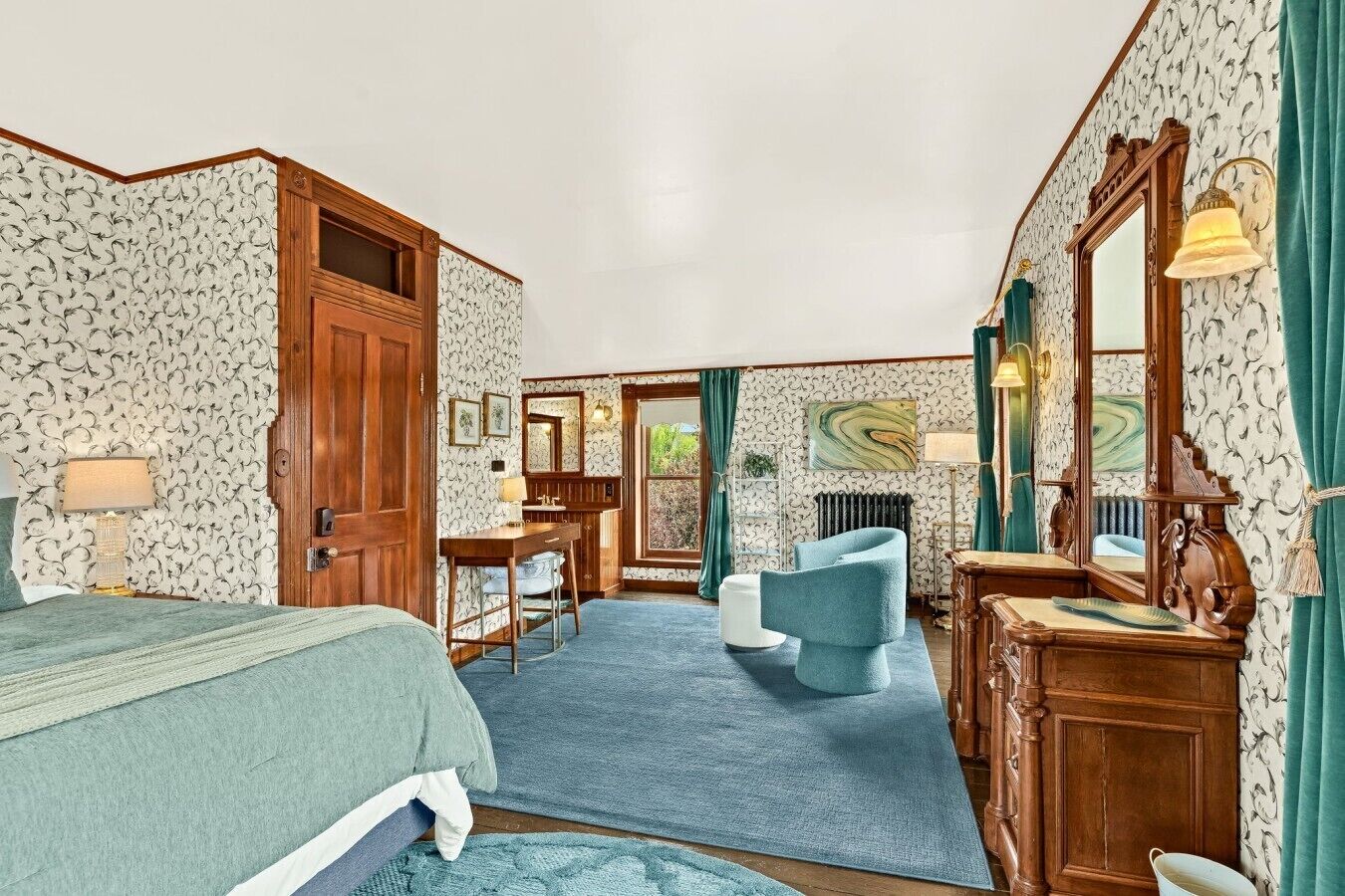 A hotel room with a bed, a desk, a chair, a dresser, and a mirror.