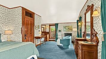 A hotel room with a bed, a desk, a chair, a dresser, and a mirror.