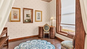 A room with a wooden ceiling, a large window with a view, a patterned rug, and a wooden cabinet with drawers.