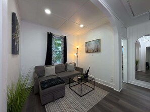 A modern living room with a sectional sofa, a coffee table, a floor lamp, and a painting on the wall.