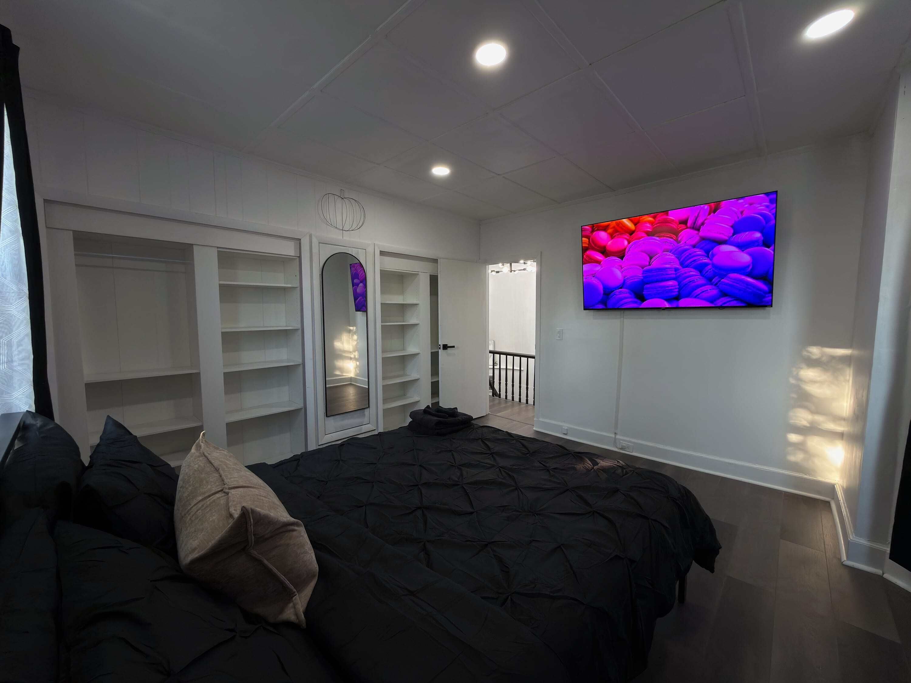 A bedroom with a bed, a wardrobe, a TV, and a door leading to another room.