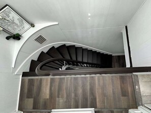 Eine Wendeltreppe mit hölzernem Geländer und einem an der Wand befestigten Bilderrahmen.