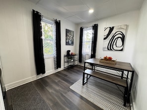 A modern living room with a dark wood floor, a black metal table, and a large abstract painting.