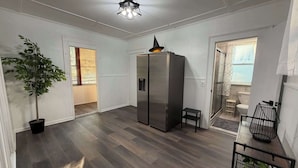 A modern kitchen with a built-in refrigerator, a potted plant, and a dining area with a small table and chair.