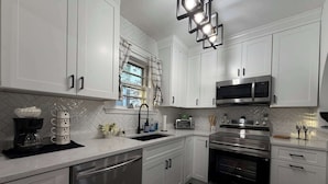 A modern kitchen with white cabinets, stainless steel appliances, a dishwasher, and a microwave.