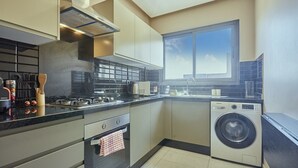 Una cocina moderna con horno integrado, lavadora y un amplio ventanal que proporciona luz natural.