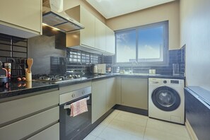 A modern kitchen with a built-in oven, a washing machine, and a large window providing natural light. - Casablanca 2BR | Free Parking Near Maarif (Casablanca)