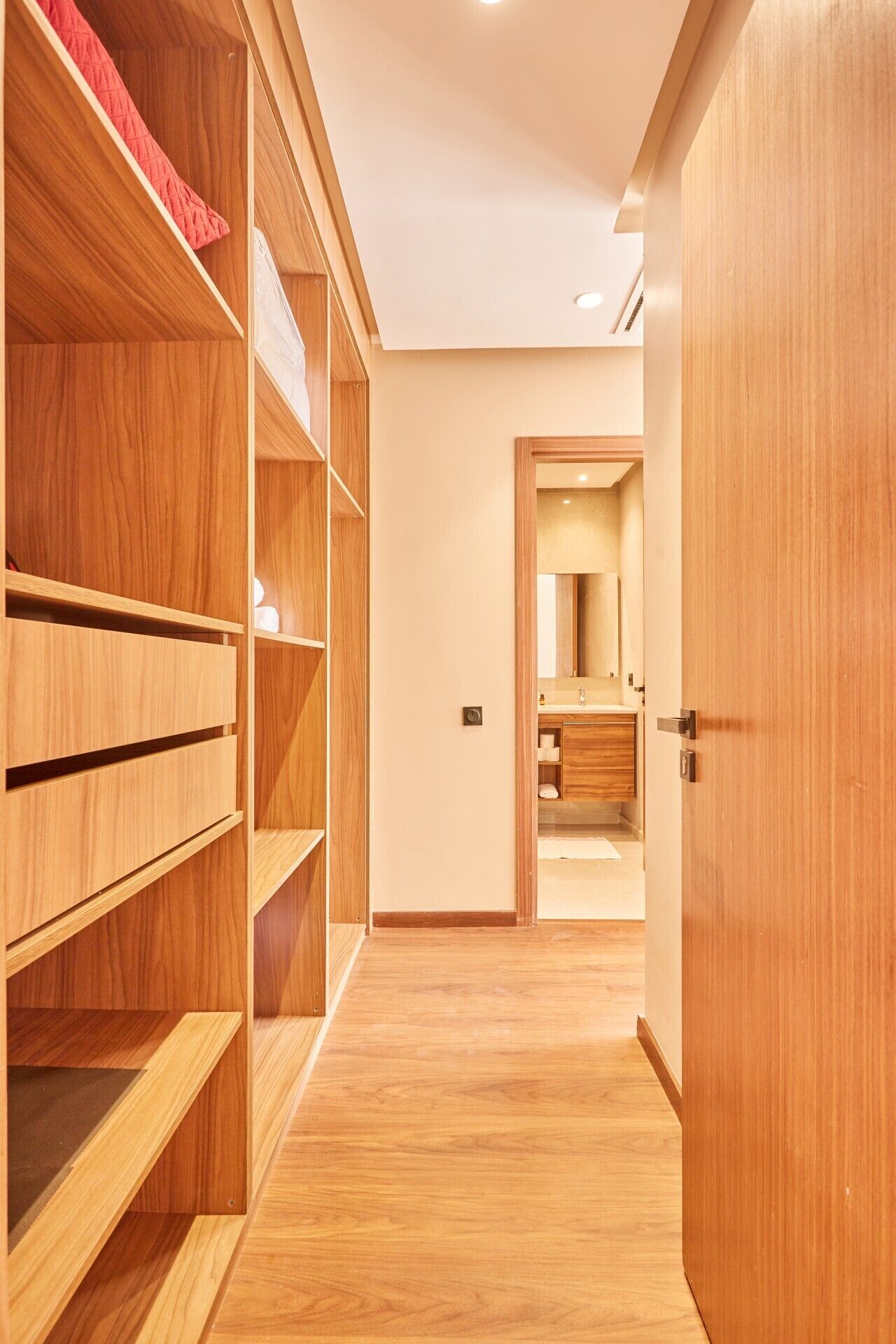 A hallway with wooden shelving units and a bathroom visible through an open door.