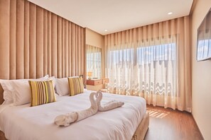 Une chambre d’hôtel avec un grand lit, une table de chevet et une vue sur l’extérieur à travers des rideaux transparents.