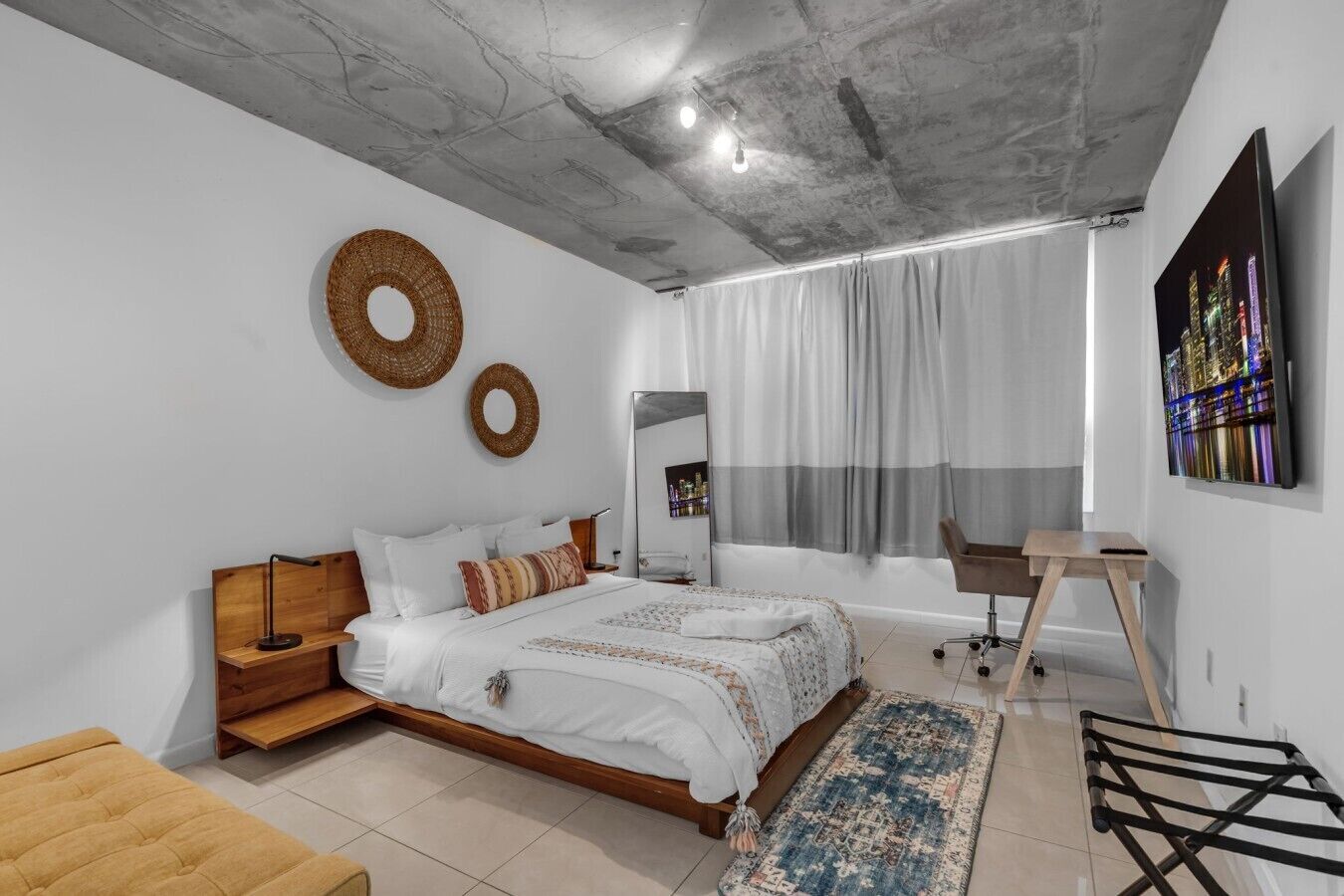 A modern bedroom with a bed, bedside tables, a desk, and a chair.