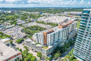 A high-rise building with multiple floors, surrounded by greenery and other buildings. - Modern Midtown Loft | Pool, Gym & Walk Everywhere (Miami)