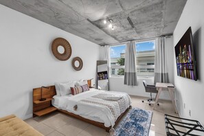 Une chambre moderne avec un lit, un bureau et une grande fenêtre avec des rideaux.