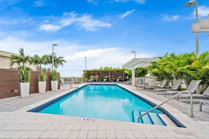 A swimming pool with a 3 ft depth marker, surrounded by lounge chairs and palm trees. - Modern Midtown Loft | Pool, Gym & Walk Everywhere (Miami)