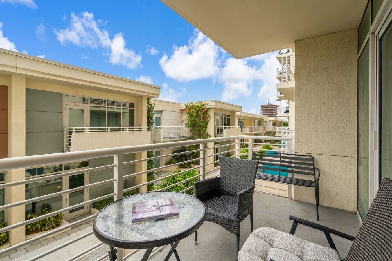 A balcony with a table, two chairs, and a view of a swimming pool.