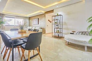 A modern living room with a dining area, a sofa, and a plant shelf. - Luxury 3BR | Prime Casablanca | Designer Stay (Casablanca)