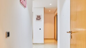 A hallway with a marble floor, a wooden door on the right, and a wall with a heart-shaped artwork and a motivational sign. - Luxury 3BR | Prime Casablanca | Designer Stay (Casablanca)