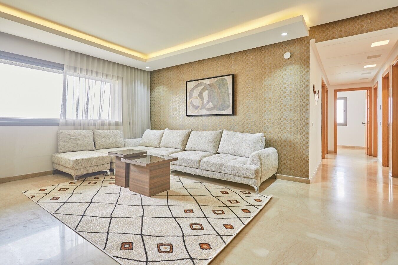 Un salon moderne avec un canapé d’angle, une table basse et un tapis à motifs.