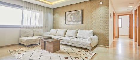 A modern living room with a sectional sofa, a coffee table, and a patterned rug.