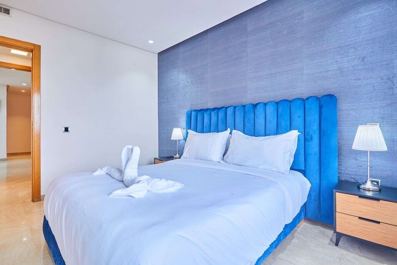 A hotel room with a large bed, a nightstand, and a lamp.
