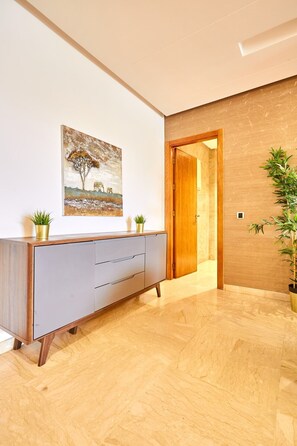 Ein modernes Interieur mit Holzboden, einem grauen Schrank mit Pflanzen, einem Gemälde und einer Holztür.