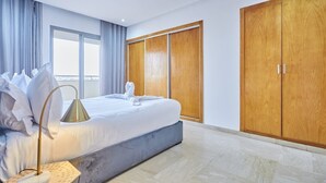 Ein Hotelzimmer mit Bett, Nachttischlampe, Kleiderschrank und einem großen Fenster.