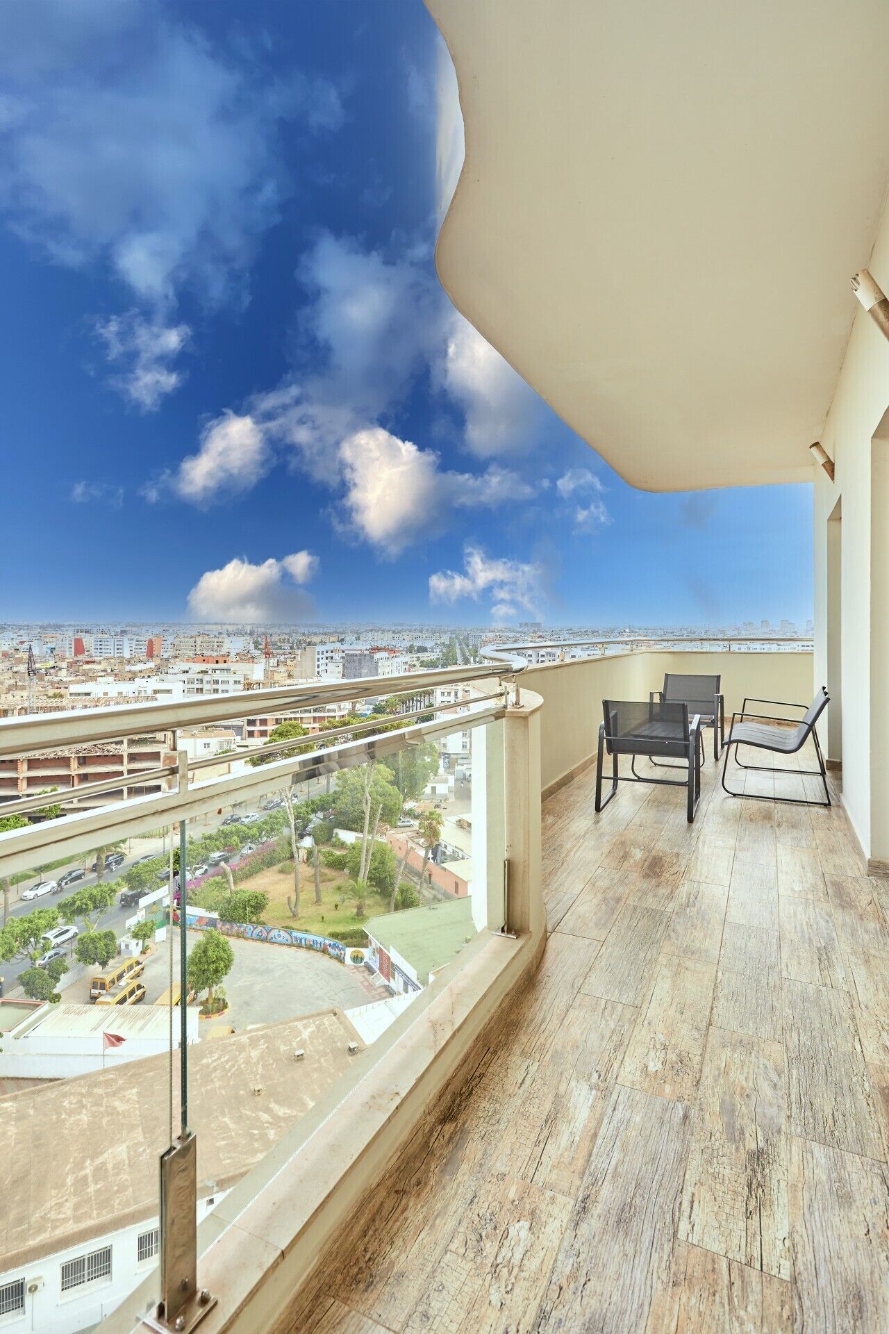 Un balcón con vista a un paisaje urbano, que incluye calles, edificios y un estacionamiento.