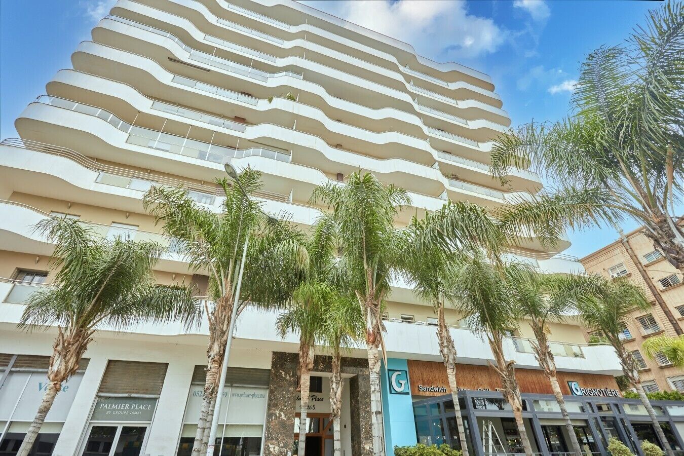 A multi-story hotel with a modern design, featuring balconies and a central atrium.