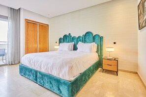 Une chambre moderne avec un grand lit, une armoire en bois, une table de chevet et une vue sur l’extérieur.