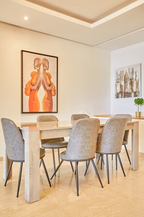 Un coin repas avec une table et des chaises, un tableau accroché au mur et une plante en pot.