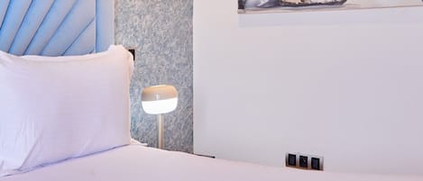 Une chambre à coucher avec un lit, une table de chevet, une lampe et un tableau au mur.