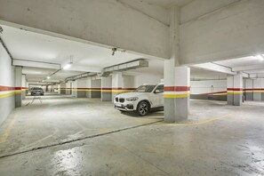 Un parking à plusieurs niveaux, avec des piliers en béton et des lignes de sécurité jaunes.