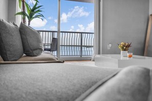 A modern hotel room with a balcony, a sofa, a small table, and a potted plant. - Stunning Bay View 3BR | Pool, Gym & Brickell (Miami)