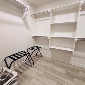 A storage closet with white shelving units and a metal bench.