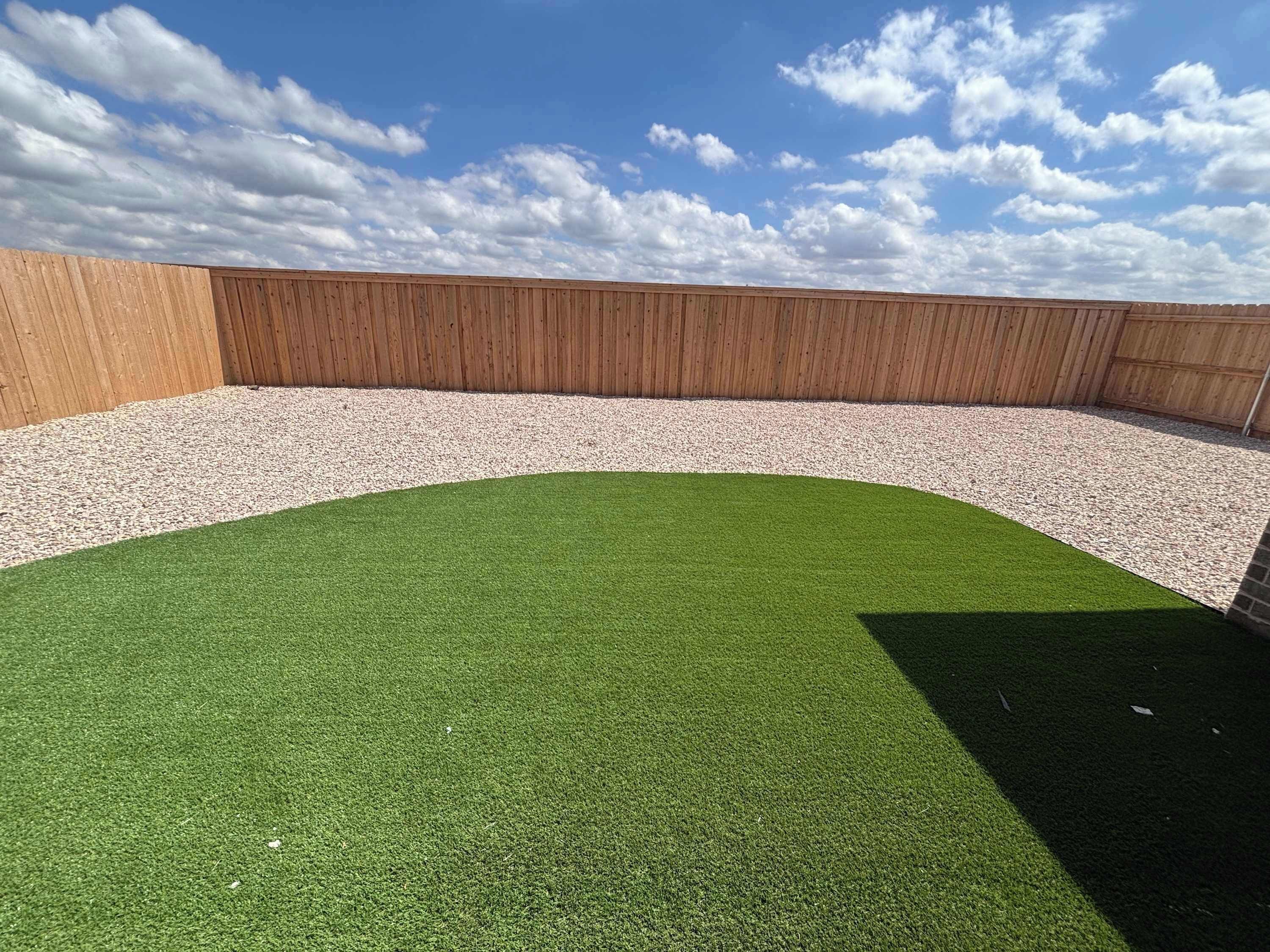 Un toit-terrasse doté d’une zone recouverte d’un gazon synthétique, d’une clôture en bois et offrant une vue sur un ciel dégagé.