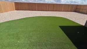 A rooftop with a green artificial turf area, a wooden fence, and a clear sky. - Colgate Cottage - 3BR/2BA - Family Friendly (Lubbock)