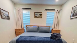 A bedroom with a bed, two bedside tables, a window with curtains, and a rug. - Colgate Cottage - 3BR/2BA - Family Friendly (Lubbock)