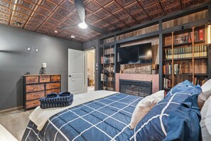 Ein Schlafzimmer mit einem Bett, einem Bücherregal, einem Kamin und einem Deckenventilator.