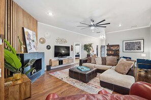 Ein modernes Wohnzimmer mit einem Flachbildfernseher, Ledersofas, einem Couchtisch und einer Wand mit Holzverkleidung.