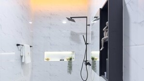 Ein modernes Badezimmer mit einem weißen Waschbecken, einem schwarzen Wasserhahn und einer Duschbrause.