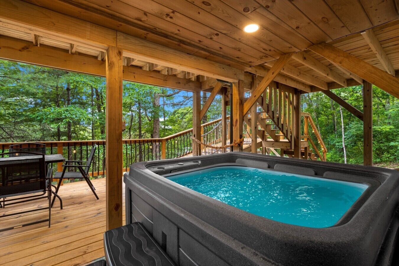 Ein Whirlpool auf einer Holzterrasse mit Blick auf einen Wald.