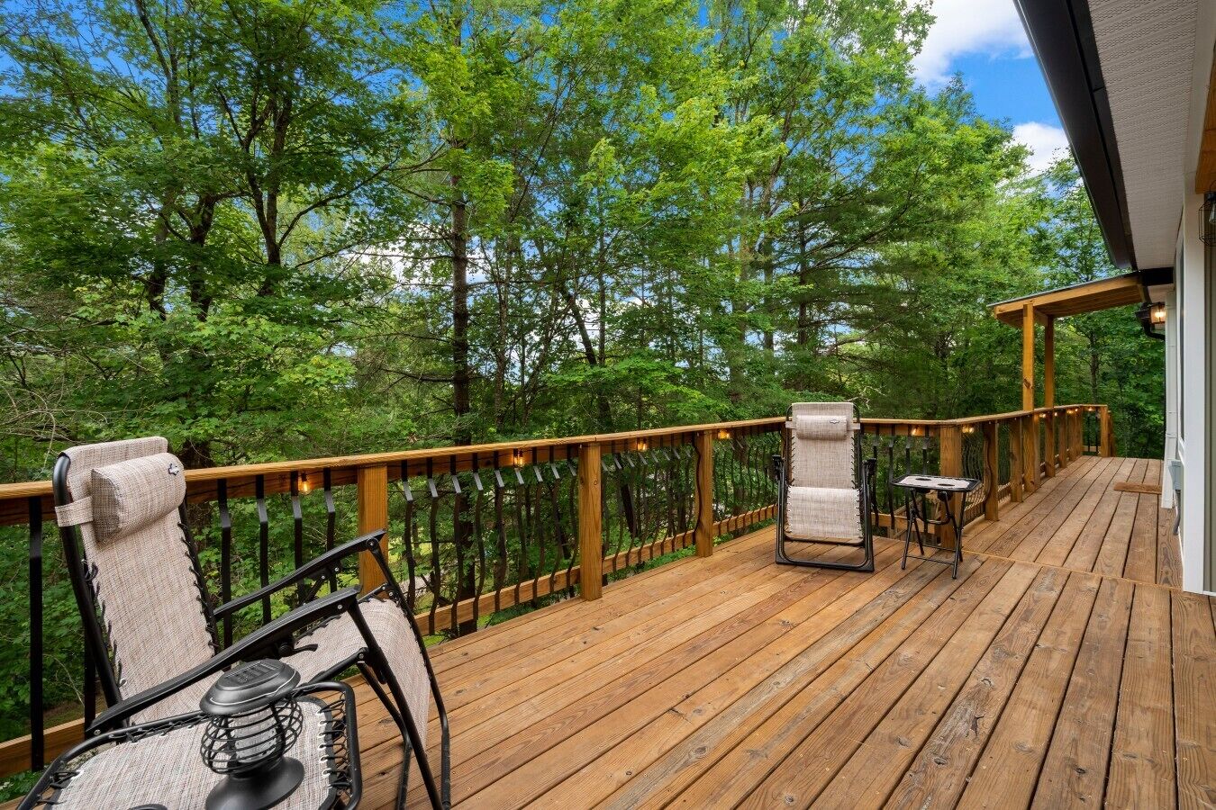 A wooden deck with outdoor seating, surrounded by trees.