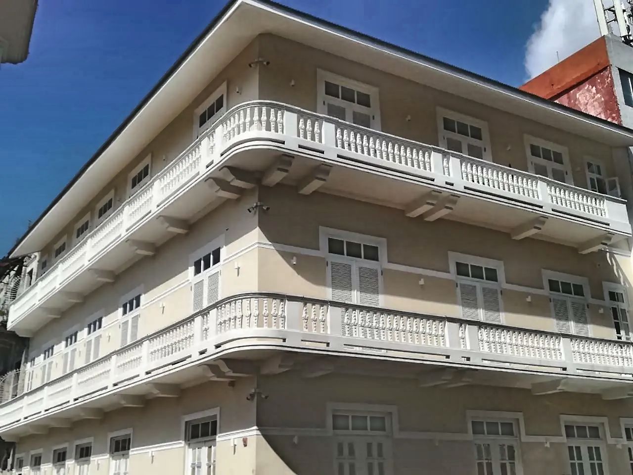 A multi-story building with balconies, windows, and a red roof.