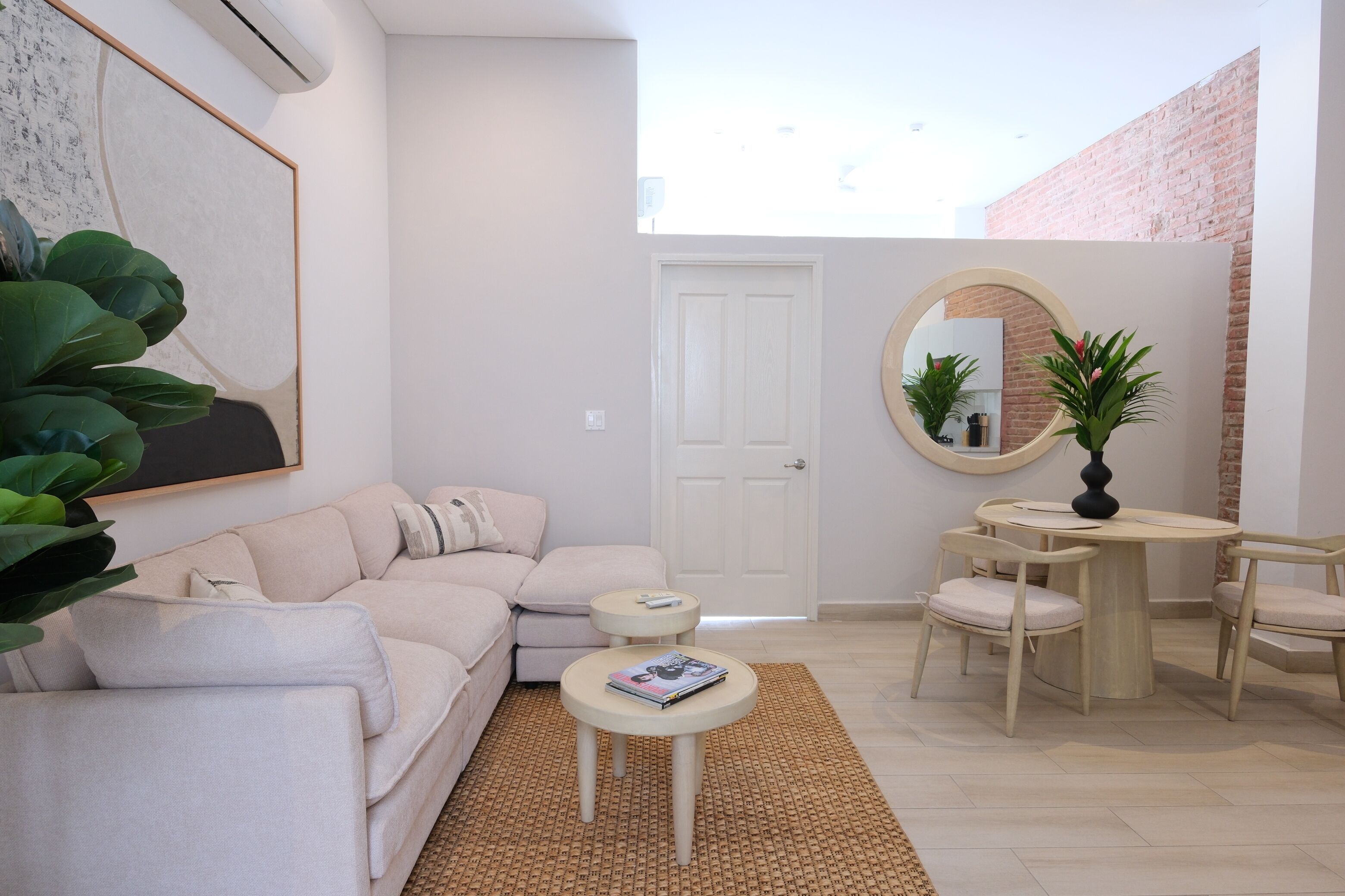 A living room with a sofa, a small round table, a mirror, and a door.