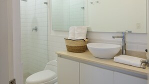 Un baño moderno con inodoro, bidé, espejo grande y lavabo.