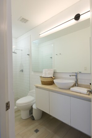A modern bathroom with a toilet, a bidet, a large mirror, and a sink with a bowl. - Casa Franco - Live in the Old Town (Panamá)